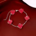 Nahaufnahme von silbernem Herz-Armband mit Perlenrand auf rotem Satinhintergrund - Silber-Lila