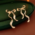 Eleganti orecchini a fiocco dorati in una scatola di velluto con design in metallo raffinato - Oro