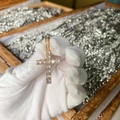 Macro detail of a gold cross pendant with cubic zirconia inlay held in gloved hands - Pendant Only / Gold