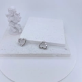 Détail de boucles d'oreilles cœur argentées avec zircons sur une surface texturée - Coeur Argenté