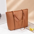 Detailed shot of brown leather tote bag with herringbone quilted pattern on marble surface - Brown