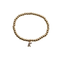 Macro view of golden bead bracelet featuring a colorful zircon-set letter K charm - Letter K