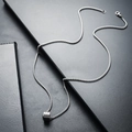 Close-up of a silver titanium steel necklace featuring a minimalist cylindrical pendant - Silver