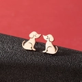 Primer plano de pendientes de perro en oro rosa sobre cuero negro y fondo rojo - Perro Lindo de Pie (778) / Rosa oro