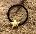 Nahaufnahme eines schwarzen elastischen Haargummis mit goldenem Stern-Anhänger - Gold Stern