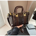 Détail d'un sac à main en cuir marron foncé avec boucles dorées et doubles anses par mannequin - Marron