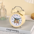 Close-up of a yellow twin bell alarm clock with cartoon animal dial on a book - 06 Yellow - Lying