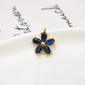 Vue macro d'un pendentif fleur en plaqué or 18K avec zircons bleu foncé pour bijoux DIY - Bleu foncé