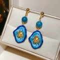 Dettaglio di orecchini a fiore dorati con pendente in smalto blu in una scatola regalo - Lega/Perno in argento sterling 925 / Stile Lungo Blu