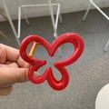 Elegant red butterfly hair claw clip with golden spring, showcased in hand - Red