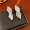Macro shot of silver diamond-shaped earrings with clear crystals on a warm background - Silver (Silver Pin)