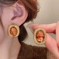 Close-up of vintage oval gold earrings with amber resin inlay and textured metallic edge - Vintage Oval Studs (37#) / Gold Amber