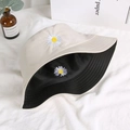 Close-up of daisy embroidery detail on a reversible cotton bucket hat in beige and black - One Size / Off White