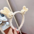 Detail of soft cream plush headband with two cute bunny ears held in a hand close-up - Headband-White Bunny