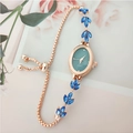 Detail of rose gold leaf bracelet watch with green dial and blue crystal accents - Blue