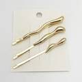 Close-up of three gold wavy metal hair clips on a white paper card packaging - 3-Piece Set / Gold