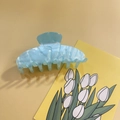 Detail view of a large translucent light blue acrylic shark hair claw clip on background - Blue
