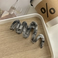 Macro detail of wave-shaped acetate hair claw clip with marble texture on wooden tray - Ink