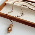 Primer plano de collar con colgante de oso de peluche marrón con perlas y cristal en caja - Marrón