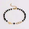Dettaglio del bracciale dorato con perline nere e ciondoli a cuore e infinito incisi - Stile Cuore EKG + Infinito
