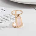 Dettaglio di un anello geometrico dorato con un cristallo rosa rettangolare su bianco - Taglia unica / Cristallo Rosa/Oro Lucido