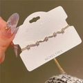 Close-up of golden bracelet with wavy metal links and sparkling white zircon stones - 14K Gold Plated Copper / Gold White