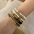 Close-up of bohemian beaded bracelet set in gold, black and white layered on wrist - Black and White