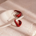 Detailed close-up of dark red U-shaped geometric earrings on a stone surface - Red Oil Drip Geometric Style