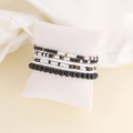 Macro shot of multi-layer white and black beaded bracelet set on a white soft velvet cushion - Black