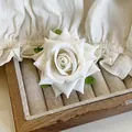 Elegant white fabric rose hair clip with layered petals and green leaves on a jewelry tray - White Rose Hair Clip