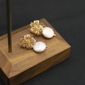 Baroque pearl earrings with golden hollow flower charms on a wooden jewelry display - Hollow Flower Stud