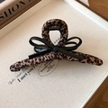 Close-up of leopard print fabric claw clip with black bow detail on a white tray - Leopard Cloth Bowknot Style