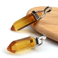 Pair of yellow natural crystal hexagonal pendants with silver metal clasps on wood - Transparent Tea