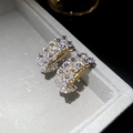 Macro detail of gold C-shape hoop earrings with double-row cubic zirconia in a jewelry box - Gold / Gold