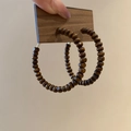Macro shot of dark brown wooden bead hoop earrings on cardboard holder for display - 9# Coffee