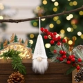 Close-up of a handmade knitted Christmas gnome ornament with white beard on a pine tree - White Style B