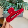 Detail of a large red hollow teardrop hair claw clip held in hand for hairstyle fix - China Red