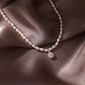 Detailed macro view of seed pearl necklace with a teardrop zircon pendant on brown silk - Silver Drop (Pearl Style)