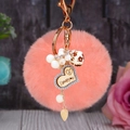Détail d'un porte-clés en fourrure rose avec pendentif en forme de cœur doré - Cœur en bois + Pompon rose clair