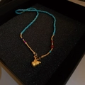 Détail du collier en perles bleu-vert avec pendentif gourde dorée sur fond noir - Style Pendentif Calebasse Doré Bleu Vert (13# Collier-Or-Bleu)
