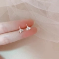 Macro detail of silver ginkgo leaf stud earrings held by fingers to show small size - Ginkgo / Silver