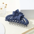 Macro detail of a dark blue matte sunflower hair claw clip on white props - Blue