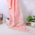 Detailed view of pink muslin baby blanket with fringe tassels and soft crinkle texture - Watermelon red