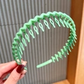 Close-up of a light green wavy non-slip headband with teeth for women's hair styling - Green