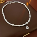 Collier de perles élégant avec pendentif en zircone carré sur une boîte à bijoux - Collier en Perles Avec Pendentif en Zircone