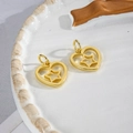 Macro detail of gold-plated hollow heart and star pendants on a ceramic tray - Heart Star Gold