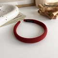 Detailed close-up of a handmade red sponge headband with a black woven logo tag - Red