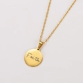 Macro detail of a polished gold round pendant with Faith engraving on a white surface - Gold Color Faith Engraved