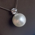 Macro-detail van een gepolijste witte parel en diamanten hanger aan een zilveren schakelketting - Ketting