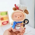 Labubu plush doll in beige chef outfit with blue polka dot scarf and small frying pan - Cute Baby Fried Egg Pendant / First And Second Generation Keychains Are Compatible With La Cloth Dolls. Dolls Not Included.